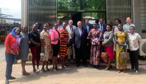 Two standing rows of primarily black people in business attire smiling at the camera. The group, which includes Harriet Dumba, are advocates for the 35% women inclusion at R-JMEC.