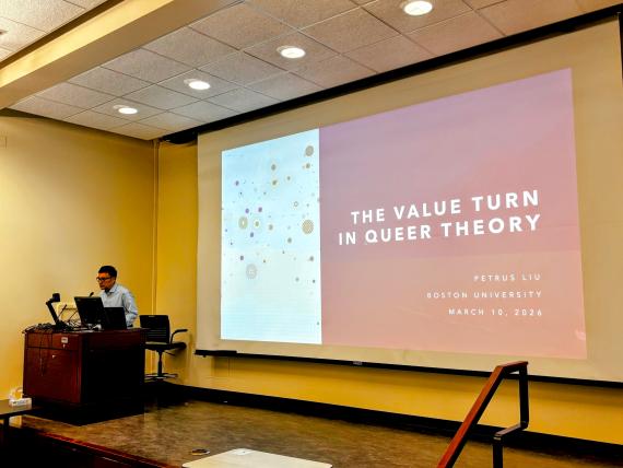Petrus Liu presents at a podium in a lecture hall, standing beside a projected slide reading “The Value Turn in Queer Theory,” with his name, Boston University, and the date displayed.