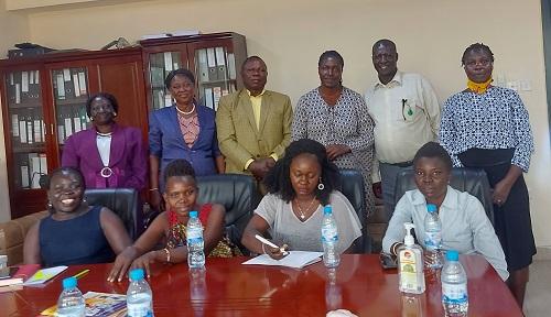 Two rows of black people in business attire (front row seated, back row standing) lobbying for the HIV Bill at Parliament. Harriet Dumba is standing in the back row to the far right. 