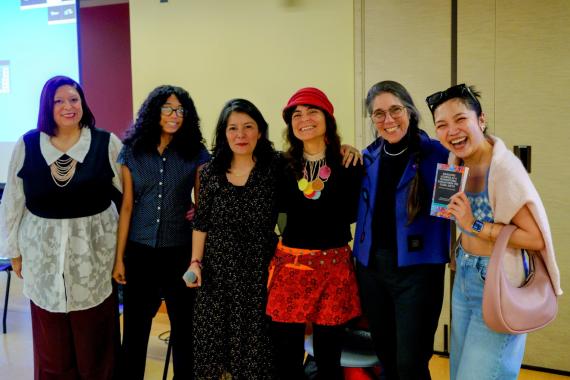 Speakers and a graduate student pose together at a GWSS book launch, holding a copy of Navigating Academia as a Transnational Scholar from the Global South.