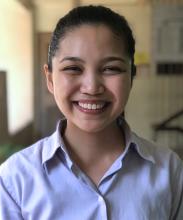 Upper body shot of Marielle Marcaida with her hair slicked back into a ponytail, wearing a white collared shirt, and smiling at the camera.