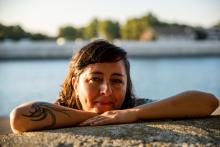 Dr. Burneo Salazar with her chin propped up on her crossed arms which are resting on a cement wall. She's in a body of water.