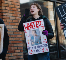 Daisy Federspiel-Baier holding a protest sign and chanting outside a Starbucks store.