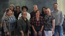 Ten GWSS faculty and staff members pose together during the 2025 faculty retreat, gathered around a wooden table in a modern meeting room with a chalkboard wall. The group reflects the department’s collaborative and welcoming spirit.