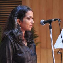 Sumangala Damodaran from waist up and in front of a microphone