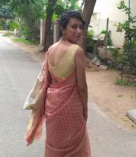 Akanksha Misra walking down a rural street, turning to face the camera over her shoulder.