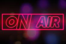 Hollow neon pink text reading "On Air" inside a pink box with blurry colorful dots in the background