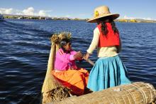 Woman and Child on Traditional Boat on Body of Water in South America 