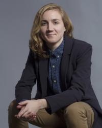 Recent Ph.D. in Feminist Studies | Long-haired person wearing blue blazer looks into camera while smiling