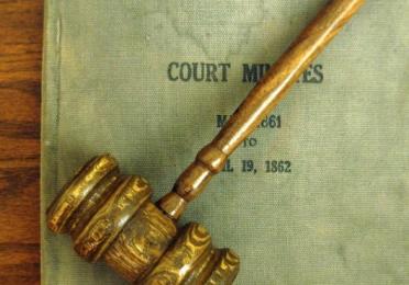 A gavel lying on a book titled "Court Minutes"