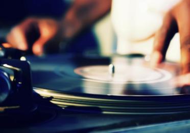 Close-up of hands manipulating a vinyl record on a turntable.