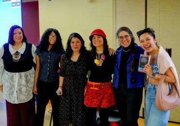 Speakers and a graduate student pose together at a GWSS book launch, holding a copy of Navigating Academia as a Transnational Scholar from the Global South.