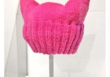 A knitted pink pussyhat on a display stand.