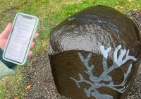  a student holding their cellphone in front of Chloë Bass' artwork