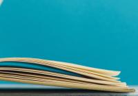 Artistic image of beige book that has fallen open with a teal blue background