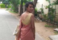 Akanksha Misra walking down a rural street, turning to face the camera over her shoulder.