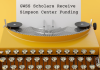 Typewriter with a yellow background. The paper in the typewriter reads "GWSS Scholars Receive Simpson Center Funding"