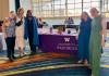 Five GWSS faculty, alumni, and friends stand smiling beside a University of Washington table at the NWSA conference.
