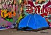 Tent setup next to a wall of graffiti