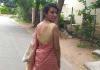 Akanksha Misra walking down a rural street, turning to face the camera over her shoulder.