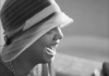 Head shot of black woman wearing a bonnet, looking sideways and laughing 