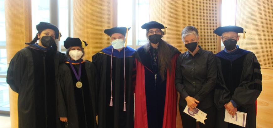 6 GWSS Faculty Members standing next to each other wearing graduation robes and masks and smiling