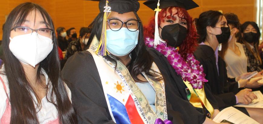GWSS Graduates: Students sitting, wearing caps and gowns, and smiling at the camera