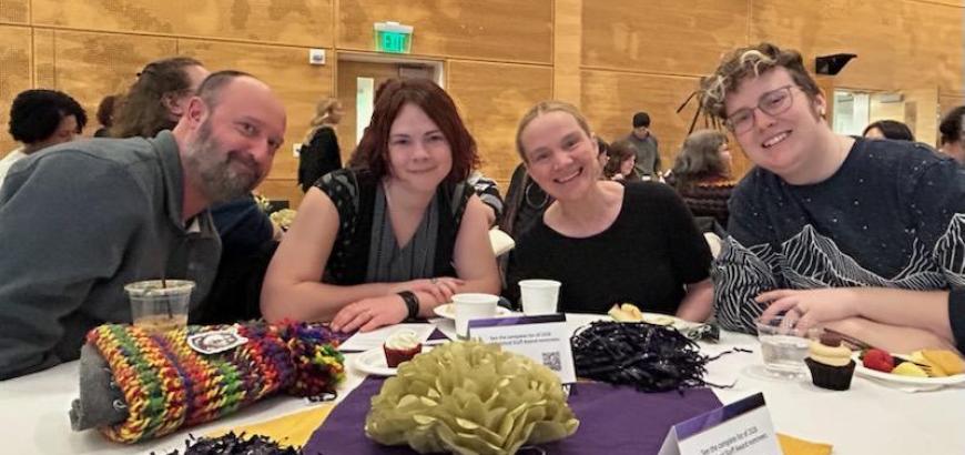 Group of 4 sitting at table smiling at camera