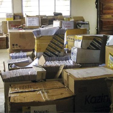 Piles of unorganized boxes and files in a room.