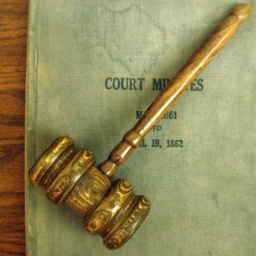 A gavel lying on a book titled "Court Minutes"
