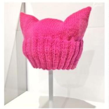 A knitted pink pussyhat on a display stand.